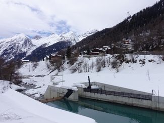 Wasserfassung in Winterlandschaft, im Hintergrund das Dorf Wiler.